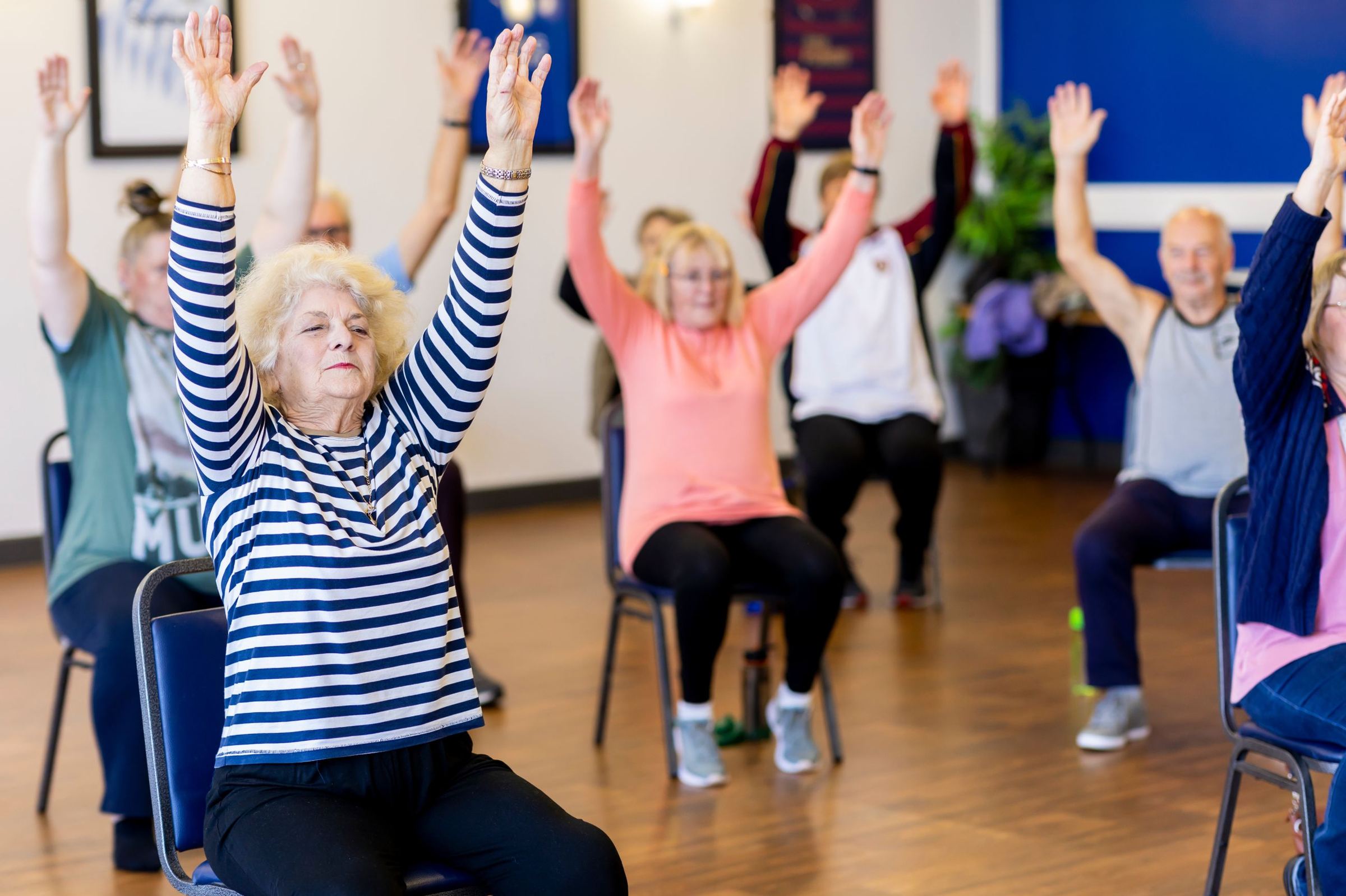 Older adults raising their arms together during a group exercise class.